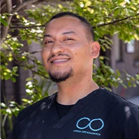 Smiling male dental team member in black scrubs outdoors