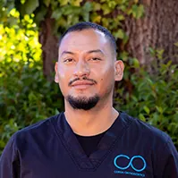 Smiling male dental team member in black scrubs outdoors